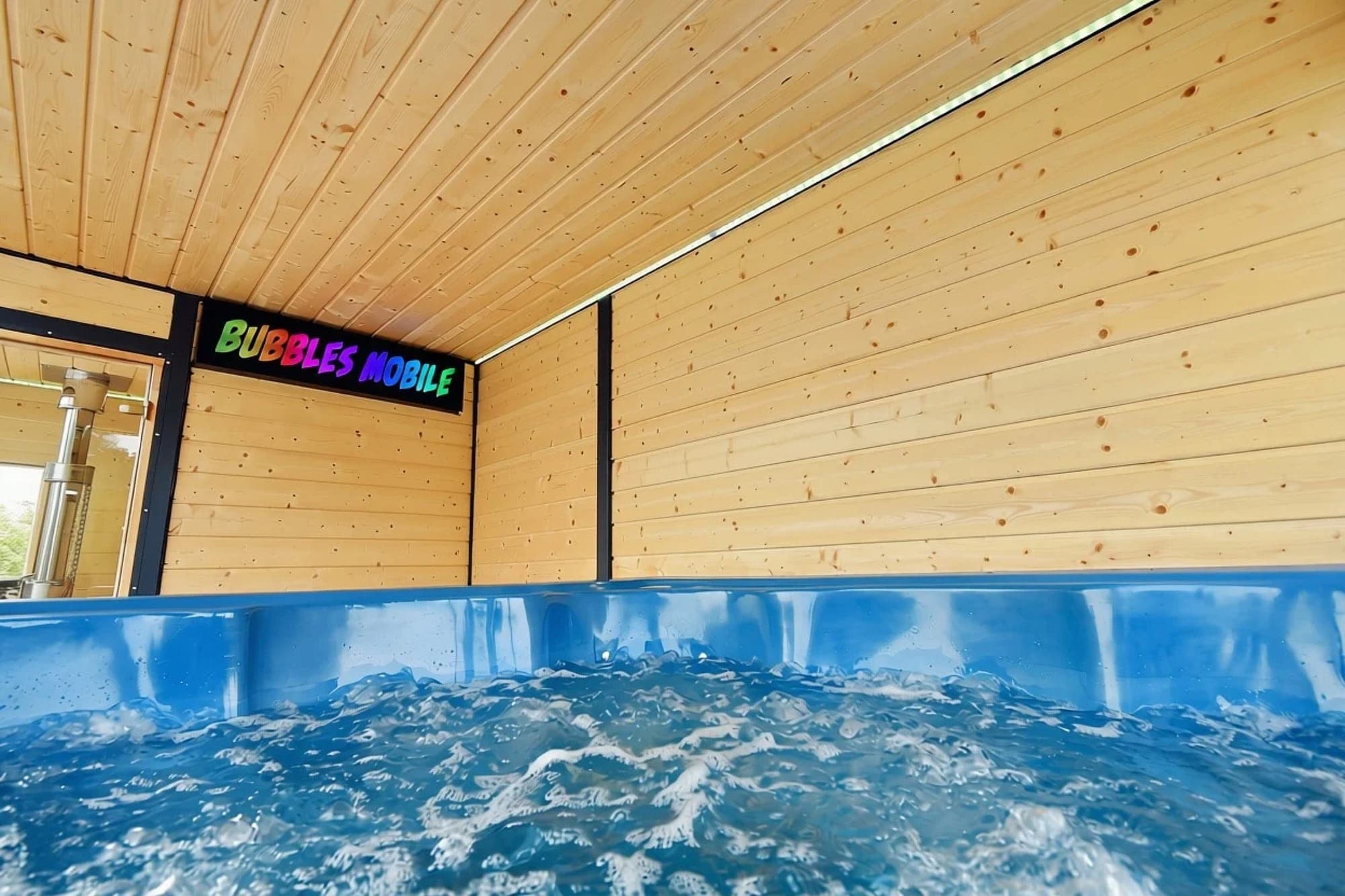 Niebieskie jacuzzi z wirującą wodą, nad nim ściana i sufit z jasnego drewna.